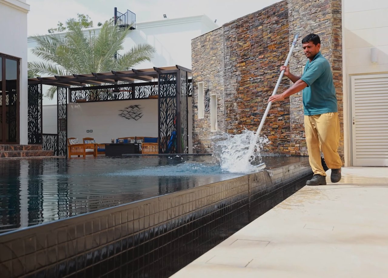 Technician brushing down pool tiles and decking